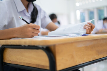 Wall Mural - Woman Asian Hands Student testing in exam on exercise taking at high school or university in test room and Writing document exams classroom, back to school and evaluation measurement in education