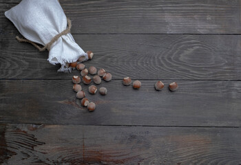 Wall Mural - Canvas bag with hazelnuts on a wooden table. Wooden table with hazelnuts in a bag.