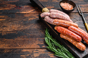 Raw homemade sausages on a cutting board. Dark wooden background. Top view. Copy space