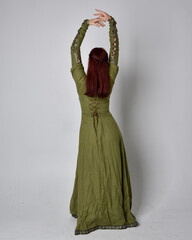 Wall Mural - full length portrait of red haired girl wearing celtic, green medieval gown. Standing pose isolated against a studio background.