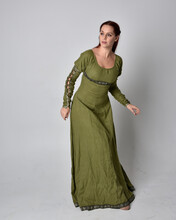 Full Length Portrait Of Red Haired Girl Wearing Celtic, Green Medieval Gown. Standing Pose Isolated Against A Studio Background.