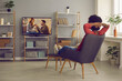 © Studio Romantic - Woman relaxing in chair at home and enjoying television soap opera with a happy ending. Young lady sitting in comfortable armchair in living-room and watching romantic series or reality show on TV