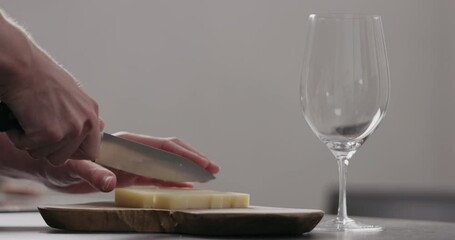 Wall Mural - Slow motion man hands cutting vintage cheese on oliveboard with wine glass