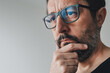 © Bits and Splits - Portrait of mid-adult contemplative man with eyeglasses, man thinking and holding chin