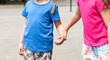 © Tomasz - Two anonymous school age children, sisters, siblings together, one girl grabbing, taking other girls hand, kids holding hands on the street. Family, togetherness and care, lifestyle simple concept