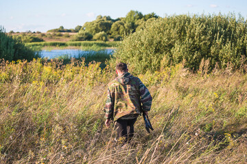 Wall Mural - Hunter with carbine back view going in scrubland