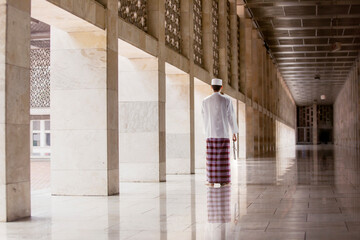 Wall Mural - Back view of Muslim man walk down mosque corridor