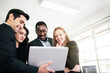 © artitwpd - African businessman and Caucasian businesswomen intend to listen to colleagues and looking on a laptop at an internal business group meeting. Diversity of businesspeople. Image with copy space.