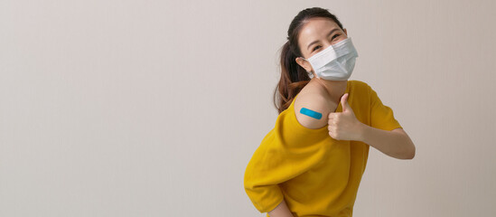 Young attractive beautiful asia female or teenage receive covid-19 anti virus vaccine in campaign vaccination safe life happy smile cheerful with blue, yellow, pink bandage on arm with copy space.