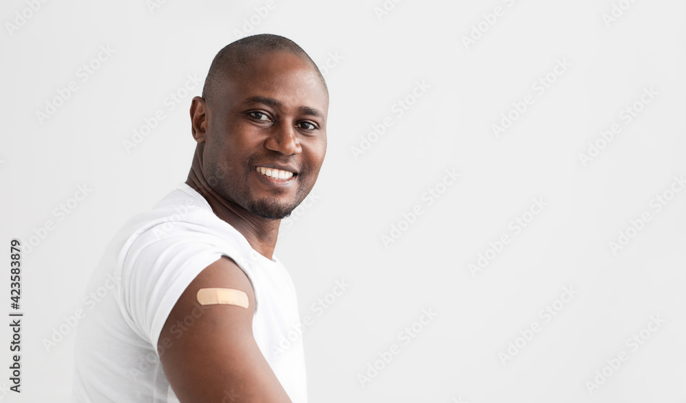 Covid-19 vaccination. Smiling african american man showing his arm with an adhesive bandage, copy space - obrazy, fototapety, plakaty 