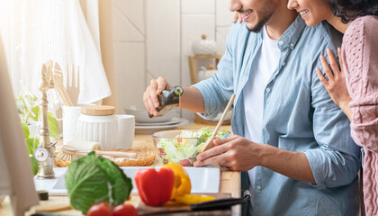 Cropped shot of young arab family preparing vegetable salad in kitchen togethe