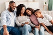 © Prostock-studio - Happy african american family holding and using smartphone