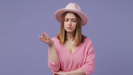 Wall Mural - Puzzled preoccupied blonde young woman 20s years old in basic pink t-shirt hat posing isolated on violet purple background studio. People lifestyle concept. Looking aside up put hand prop up on chin