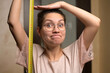 © Вячеслав Думчев - A young woman shows joy at her growth by holding a measuring tape next to her