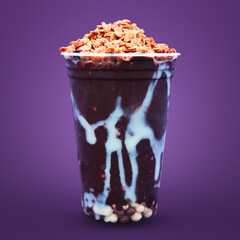 Cup of Açaí with condensed milk, granola and sweets on a purple background