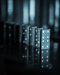 Dramatic creative image of dominos with a dark and blurry bokeh background