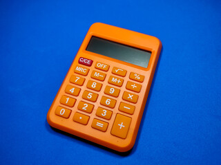 Selective focus of calculator on blue background.