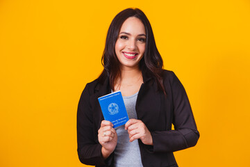 Beautiful caucasian, brazilian woman, businesswoman, smiling, holding her work card. representing job search, corporate, yes we can, yellow background