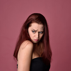 Canvas Print - Close up portrait of a red haired woman with expressive facial features on a pink studio background.