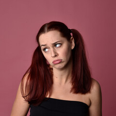 Canvas Print - Close up portrait of a red haired woman with expressive facial features on a pink studio background.