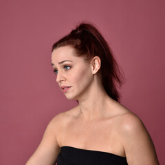 Canvas Print - Close up portrait of a red haired woman with expressive facial features on a pink studio background.