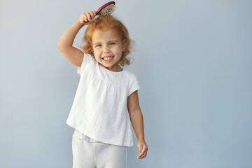 Wall Mural - Cute little girl sitting in a studio on a blue background