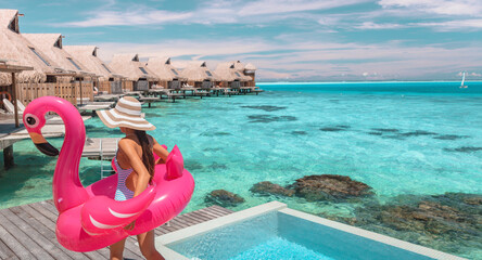 Wall Mural - Travel vacation fun tourist woman enjoying luxury summer holidays at Bora Bora overwater bungalow swimming with flamingo pool toy float at infinity pool by turquoise ocean. Tahiti getaway destination.