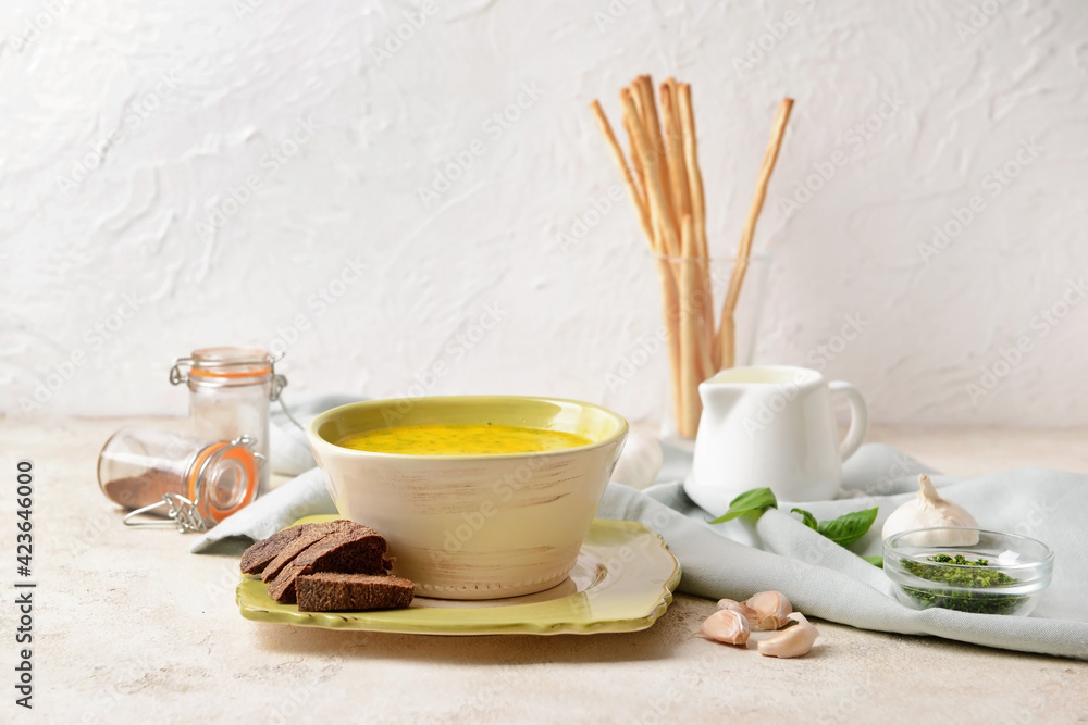 Bowl with tasty garlic cream soup on light background