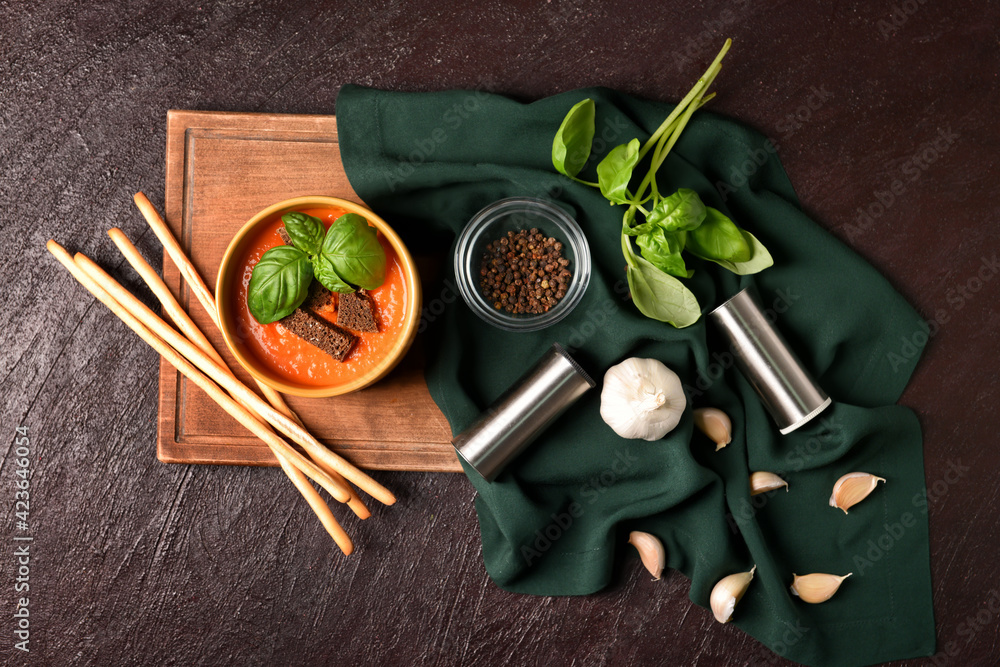 Bowl with tasty tomato cream soup on dark background