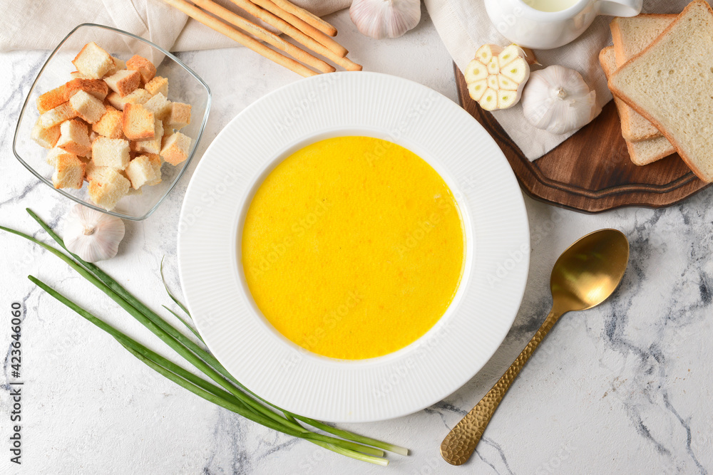 Plate with tasty garlic cream soup on light background