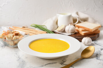 Plate with tasty garlic cream soup on light background