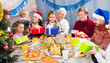 © JackF - Family members handing presents to each other during Christmas dinner