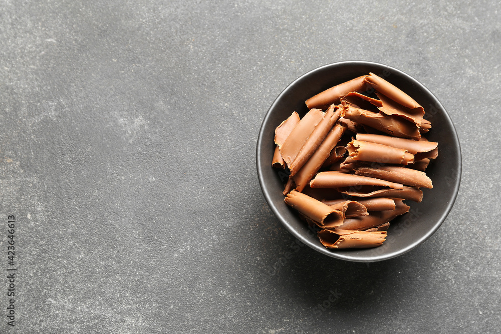 Bowl with delicious chocolate curls on dark background