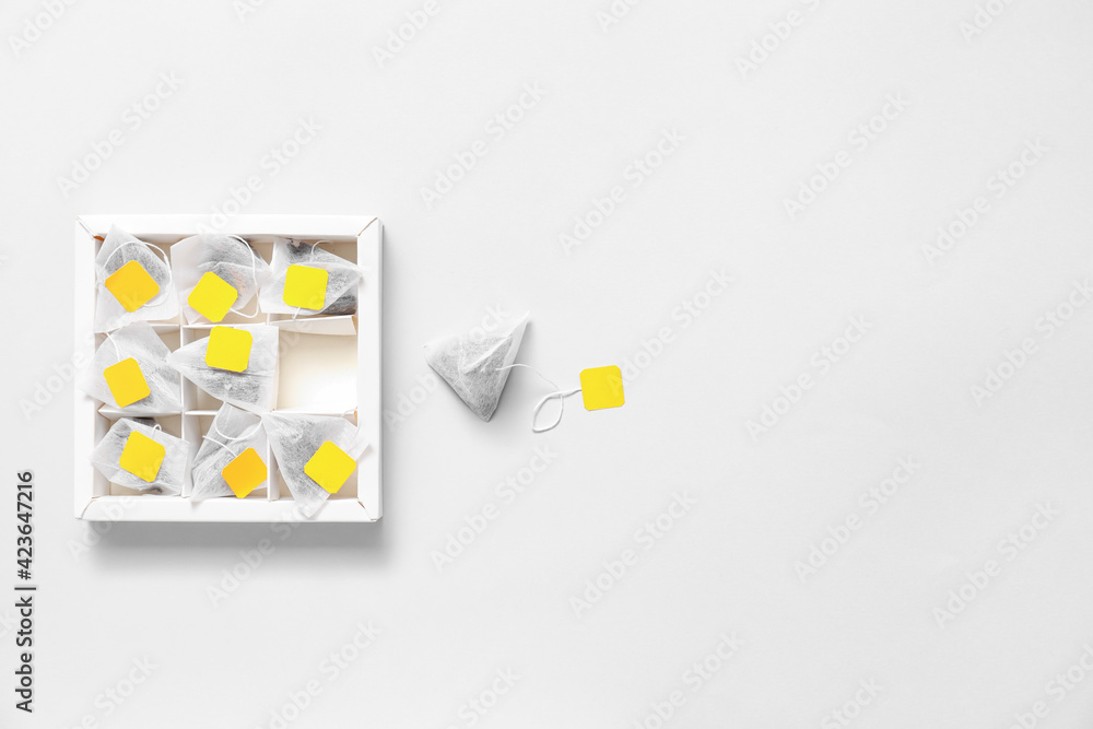 Box with tea bags on light background