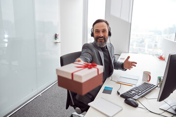 Wall Mural - Happy office worker is holding a present and smiling