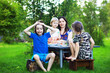 © alexkich - A young large family at a picnic on a summer morning.Mother with children is having breakfast in the park.