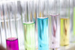 Glass test tubes with multicolored liquids standing on table in chemical laboratory closeup