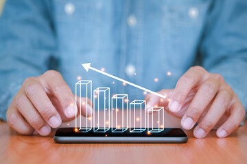 Businessman used a smartphone and touch the screen with business graph pop up on smart phone. The concept of finance and technology.