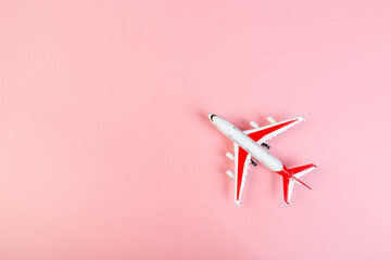 Wall Mural - toy Model of a modern airplane with red wings. tourism and travel concept. pink background top view