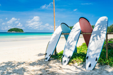 Surfboard on tropical beach with blue sky background. Summer vacation and sport extreme concept.