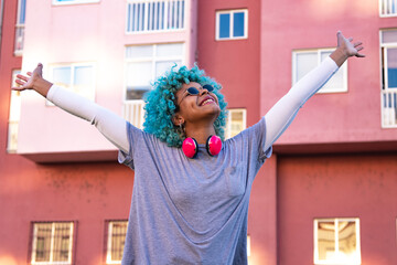 Wall Mural - afro american hipster girl listening to music with headphones in the city