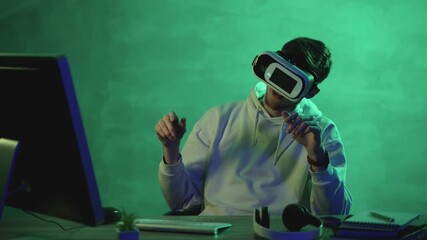 Young man using a VR headset and a computer on a colorful background