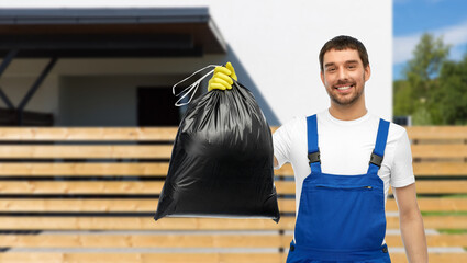 Wall Mural - profession, cleaning service and people concept - happy smiling male worker or cleaner in overall and gloves showing garbage bag over living house background