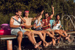 © Zoran Zeremski - Group of friends sitting on the edge of a pier having fun and enjoying a summer day at the lake.