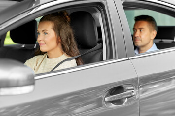 Wall Mural - transportation, vehicle and people concept - happy smiling female driver driving car with male passenger