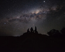 Silhouette Of A Group Of Person Sitting On A Rock Watching The Milkyway