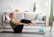 © Prostock-studio - Athletic senior woman doing abs exercises, sitting in boat yoga pose at home, free space