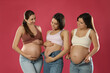 © New Africa - Happy young pregnant women on red background