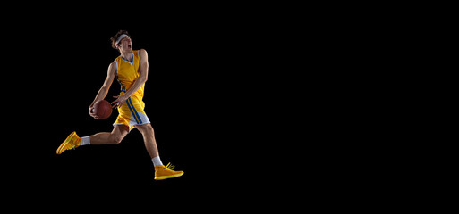 Wall Mural - Young Caucasian basketball player training isolated on black background.