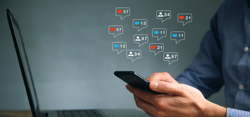 man working on computer and phone with message at social network